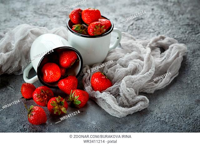 Fresh juicy delicious strawberries in enamel mugs