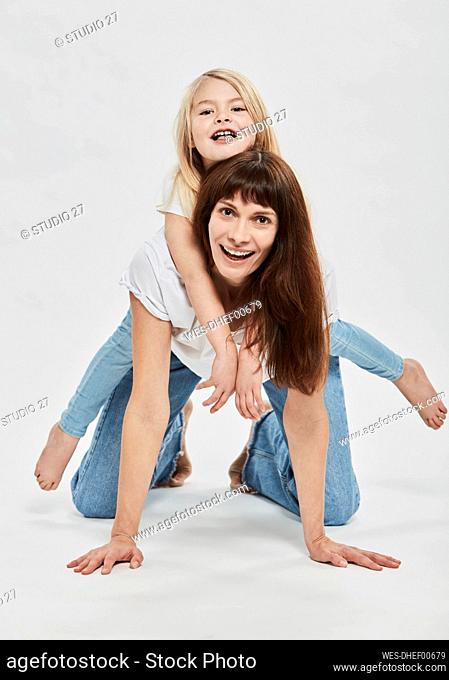 Playful mother and daughter having fun against white background
