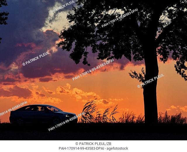 A vehicle is silhouetted against a dramatic cloudscape at sunset in the village of Sieversdorf, Germany, 13 September 2017