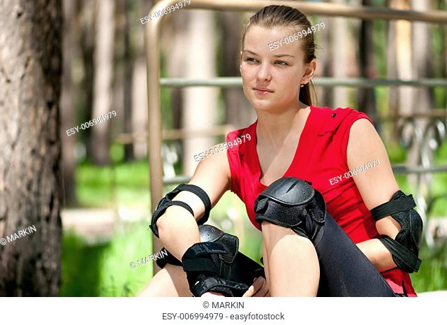 Beautiful young woman rink on roller-skate in green park on sunny summer day