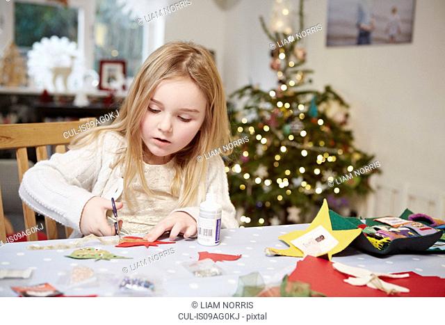 Young girl cutting out paper preparing for christmas