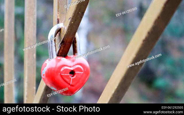 Shabby red lock in the shape of a heart. Valentine's day love concept. A padlock hanging on a metal railing is a sign of eternal love