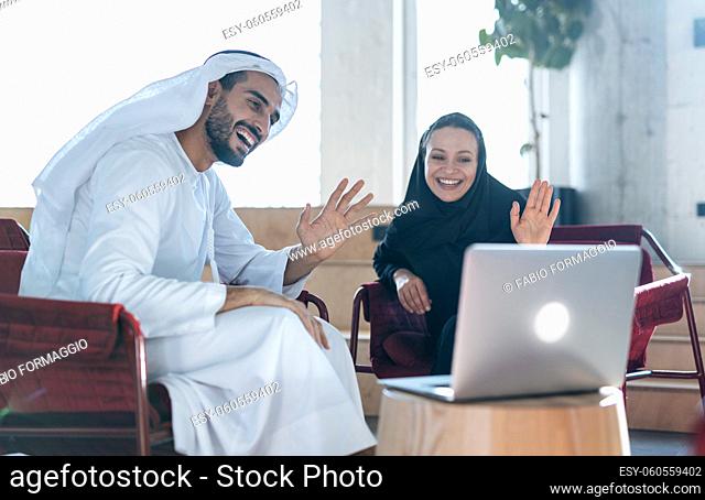 Man and woman with traditional clothes working in a business office of Dubai. Portraits of successful entrepreneurs businessman and businesswoman in formal...