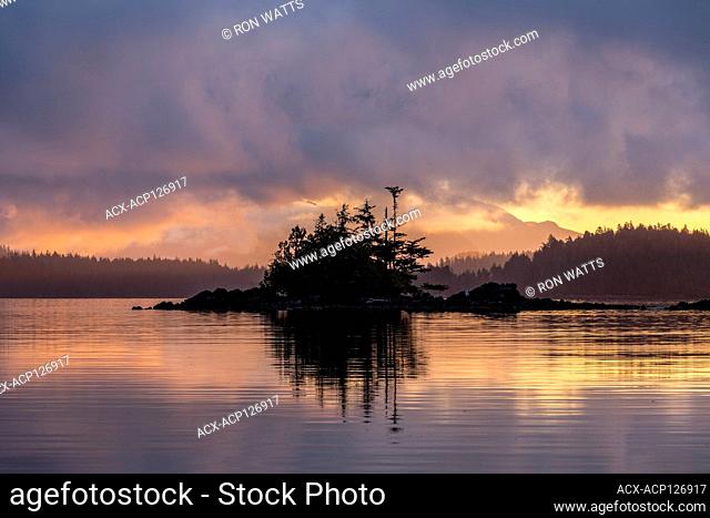 The sun rises through a cloudy sky over the Broken Islands in Pacific Rim National Park Reserve British Columbia, Canada
