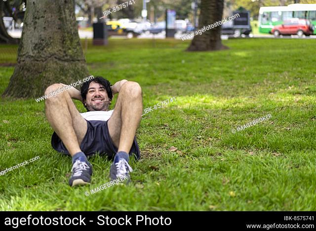 Portrait of handsome attractive mature bearded athletic latin man guy 40s doing sit-ups in the park