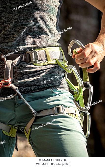 Woman preparing to climb, putting on climbing harness