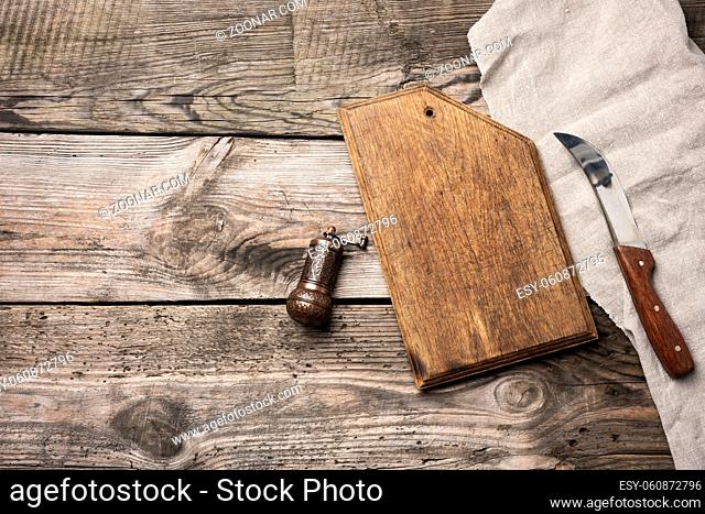 metal kitchen knife and wooden cutting board on a table made of wooden boards, top view