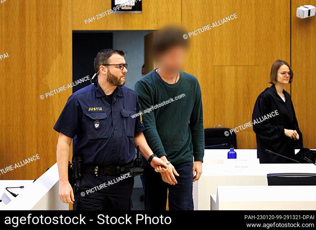 20 January 2023, Bavaria, Munich: One of two men charged with murder (M) is led into the high-security courtroom of the Munich II Regional Court before the...