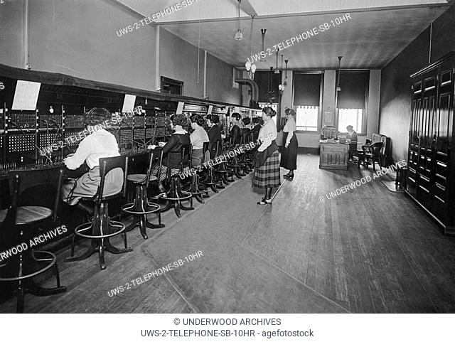 United States, c. 1915 A telephone switchboard with operators connecting the calls and two supervisors standing in back and overseeing them