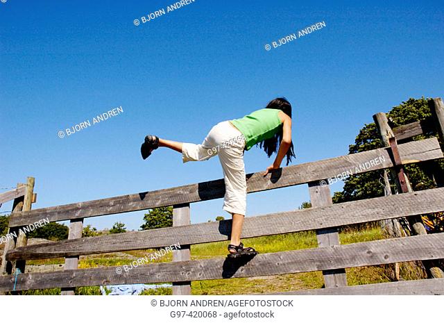 Girl climbing over a fence