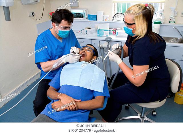 Dentist and dental nurse carrying out dental treatment on a patient