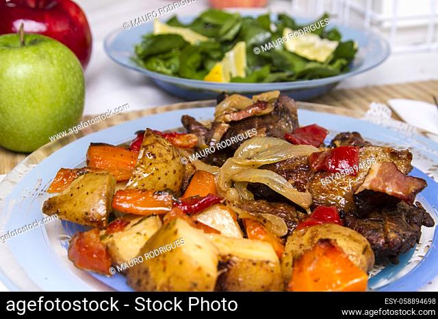 Close up view of oven baked meat with potatoes, and watercress salad