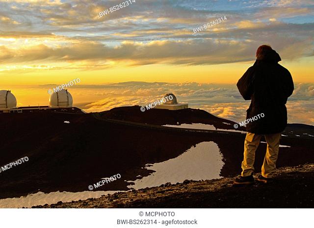 man watching the astronomical observatory on Mount Mauna Kea at sunset, USA, Hawaii