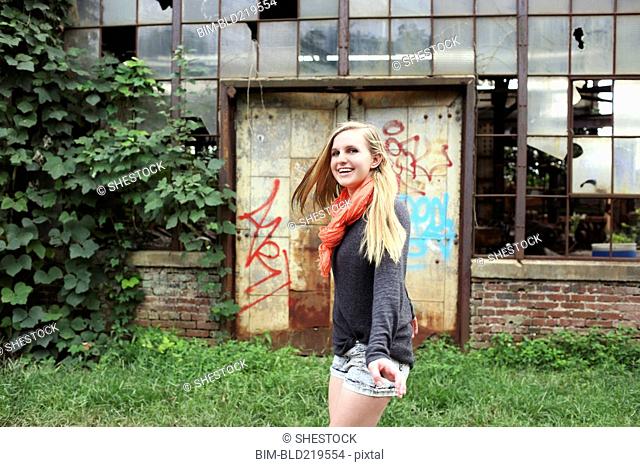 Smiling woman walking outside dilapidated building