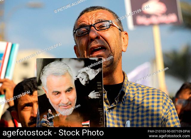 03 January 2021, Iraq, Baghdad: An Iraqi man holds a poster during a protest at Tahrir Square to commemorate the one-year anniversary of the assassination of...