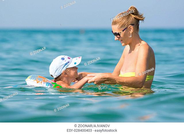 Joyful mother and daughter swimming in the sea