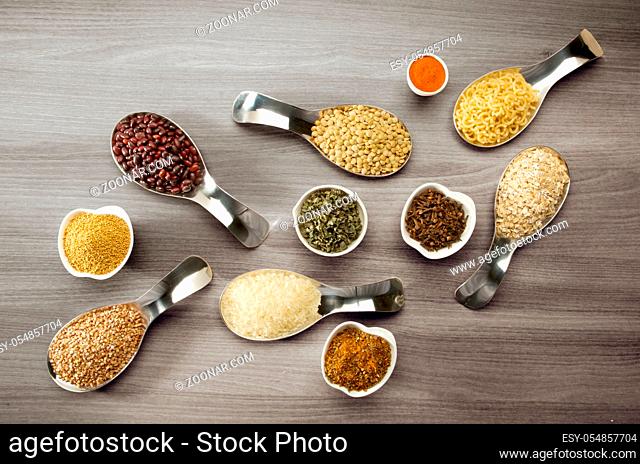BEANS RICE BUCKWHEAT SEEDS LENTILS SPICES IN SPOONS ON WOODEN BACKGROUND