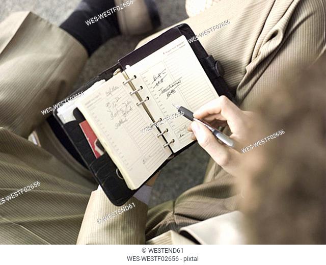Businessman holding time planner, overhead view, close-up