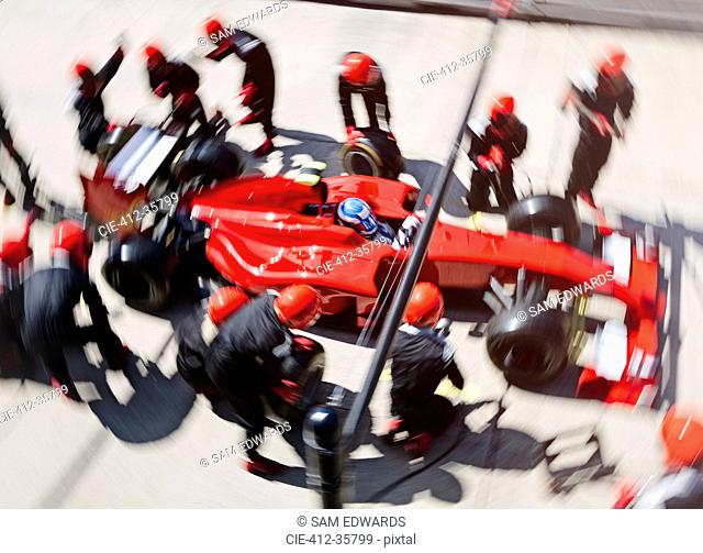 Overhead pit crew replacing tires on formula one race car in pit lane