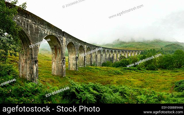 High resolution panorama of Glenfinnan railway viaduct (location from Harry Potter movie) shot from side, on overcast day with grey sky and lot of green grass...