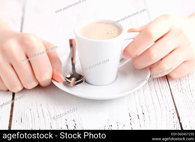 Close up female hands with cup of coffee on the table. coffee break closeup