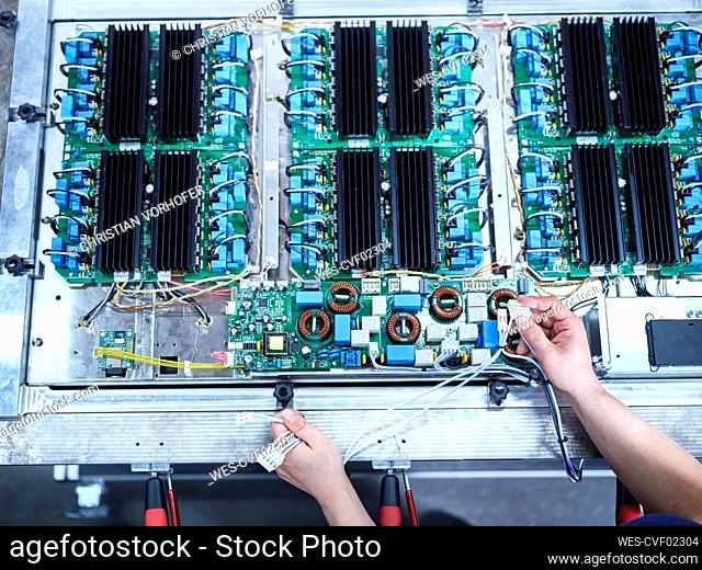 Engineer installing wires on circuit board at factory