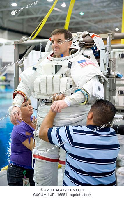 NASA astronaut Rex Walheim, STS-135 mission specialist, gets help donning a training version of his Extravehicular Mobility Unit (EMU) spacesuit in preparation...
