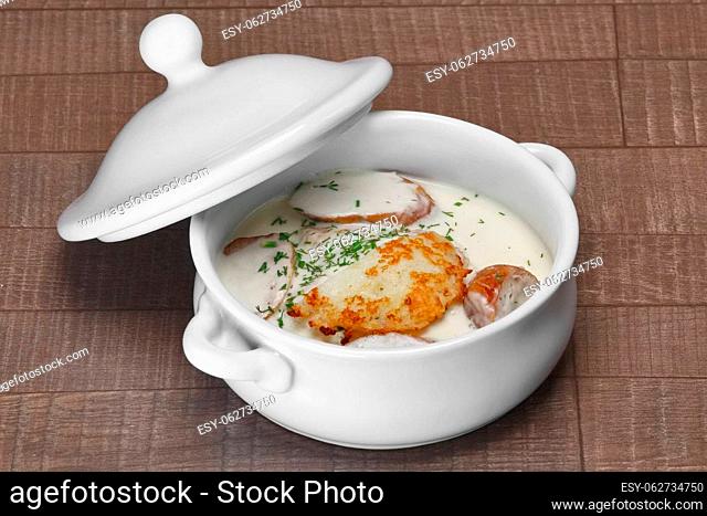 White bowl with machanka and potato pancakes on wooden table