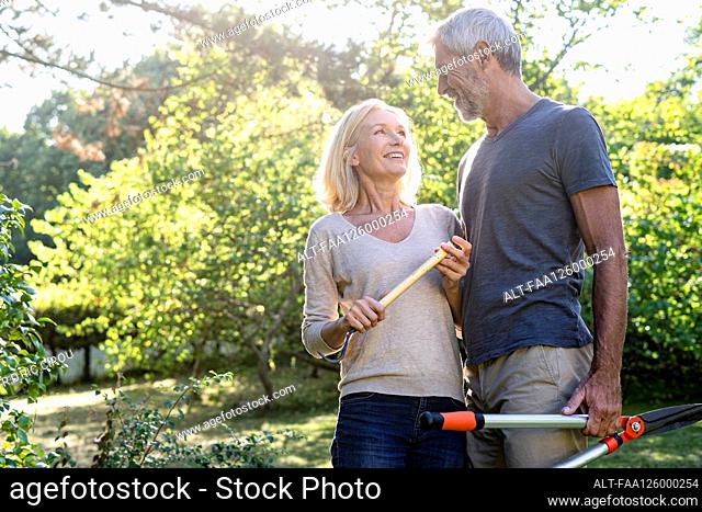 Smiling mature couple looking at each other while standing in backyard
