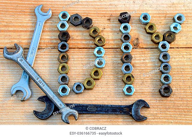 DIY (do it yourself) text from small nuts and spanners on wooden desk background