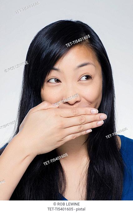 Studio portrait of young woman covering mouth