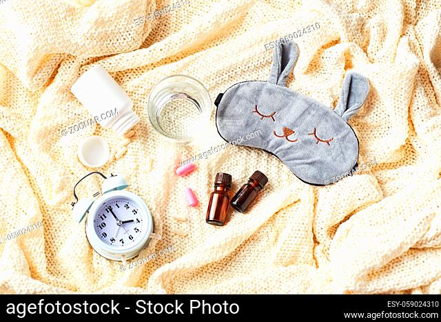 Sleeping mask, alarm clock, earplugs, essential oils and pills. Healthy night sleep creative concept. Flat lay, top view