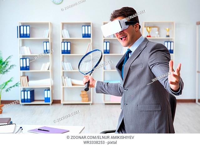 Businessman playing virtual reality tennis in office with VR goggle