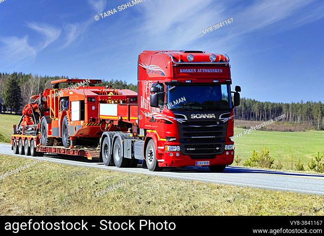 Red Scania R580 semi trailer truck transports Sandvik mining equipment on lowboy trailer along highway 52. Salo, Finland. April 18, 2019