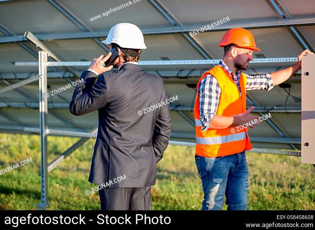 Director and engineer, solar panels construction. Head of solar station talking on phone
