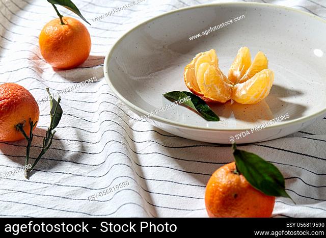 still life with mandarins on plate over drapery