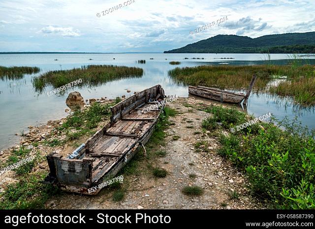 Abandoned boats on the beach with cloudscape at El Remate, Peten, Guatemala