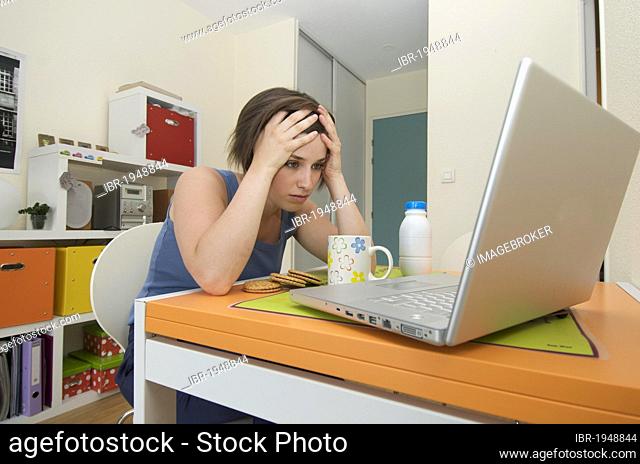 Young woman, student in her apartment, working on laptop