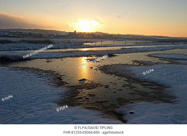View of snow covered coastal grazing marsh habitat at sunset, Salthouse, Norfolk, England, december