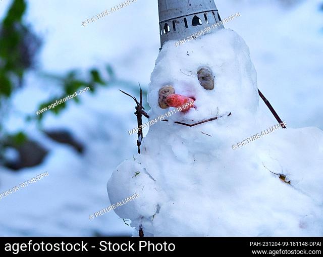 30 November 2023, Berlin: 30.11.2022, Berlin. A snowman stands in the snow in a garden on a cold, wintry November day. The snowman does not correspond to the...