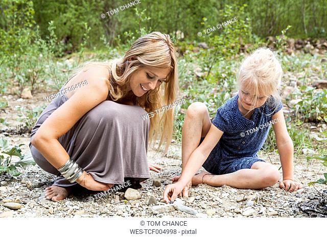 Mother and her little daughter looking for stones in nature
