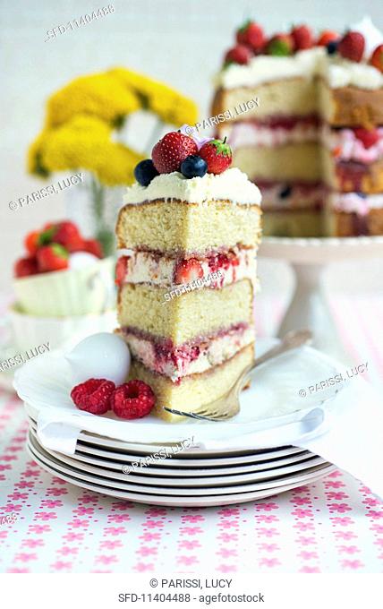 An Eton Mess layer cake with strawberries, raspberries and blueberries, sliced with a slice on a plate