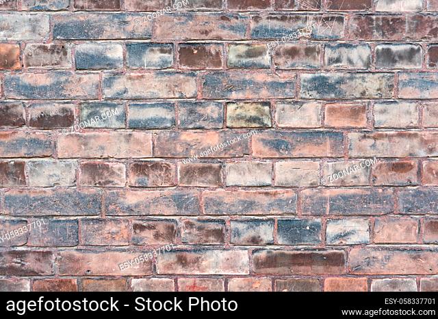 A weathered worn out moldy red stone wall in closeup