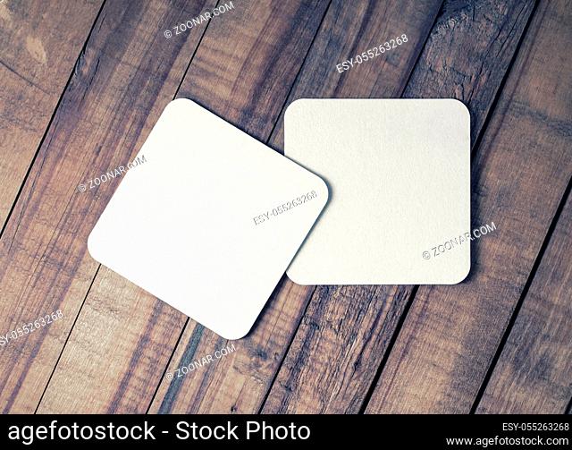 Two blank square beer coasters on vintage wooden background. Flat lay