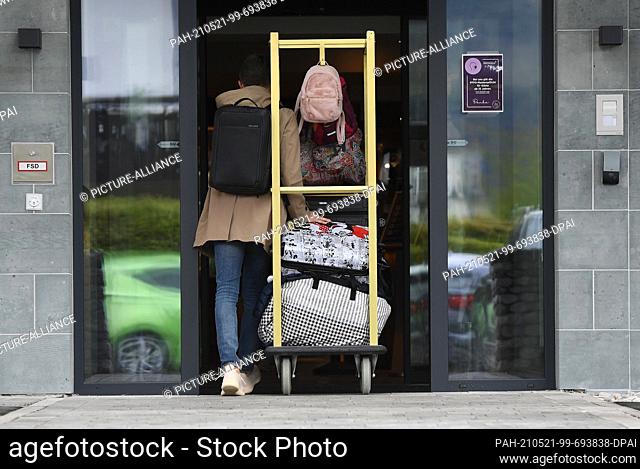 21 May 2021, Bavaria, Garmisch-Partenkirchen: A holidaymaker pushes many suitcases to a hotel entrance. As of today, hotels in Bavaria are allowed to open for...