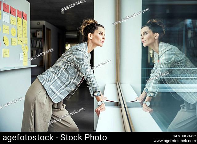 Thoughtful businesswoman looking through office window