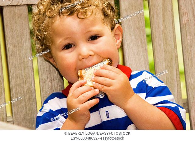 2-year-old boy eating a peanut butter sandwich