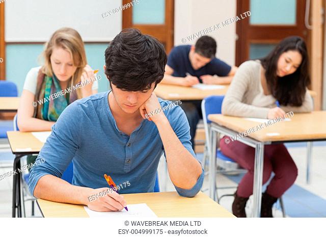 Group of students sitting an exam in exam hall in college
