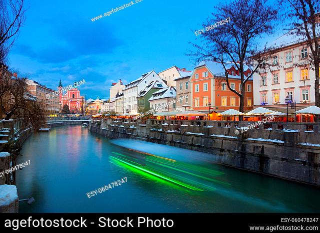 View of lively river Ljubljanica bank and Tromostovje in old city center decorated with Christmas lights at dusk. Ljubljana, Slovenia, Europe