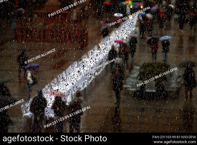 03 November 2023, Bavaria, Munich: A blank Shabbat board with pictures and names of kidnapped Israelis can be seen behind a rain-soaked window pane on...